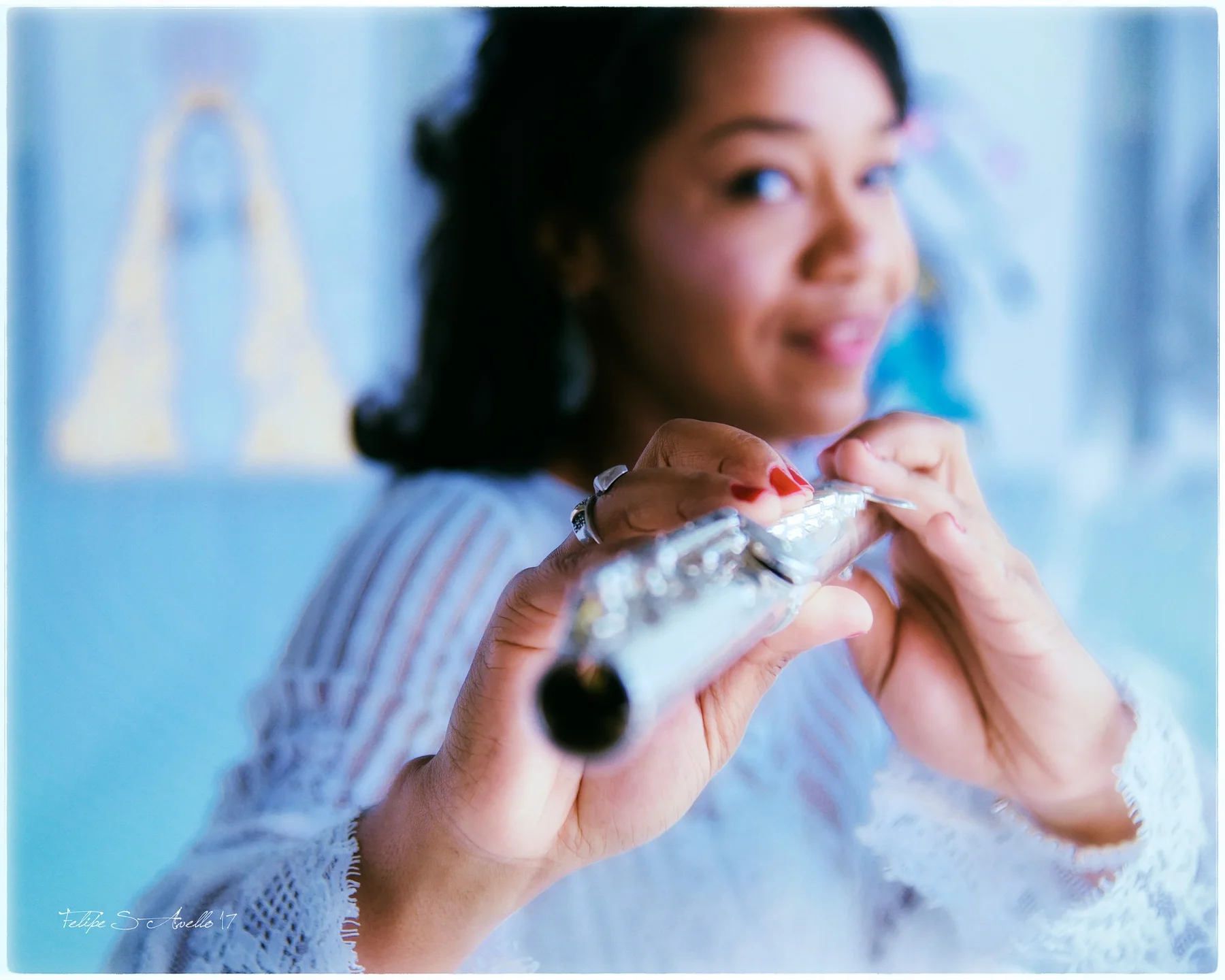 Magela Herrera holding her flute toward the camera, smiling softly in a white lace top
