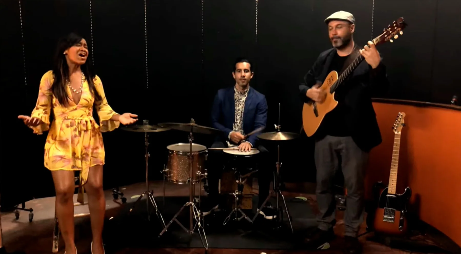 Magela Herrera singing with a drummer and a guitarist in a studio