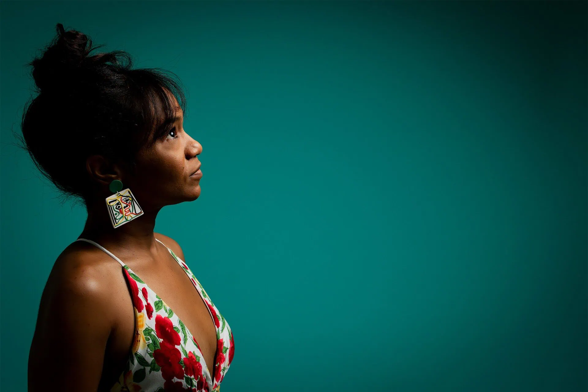 Magela Herrera in profile looking upward against a teal backdrop