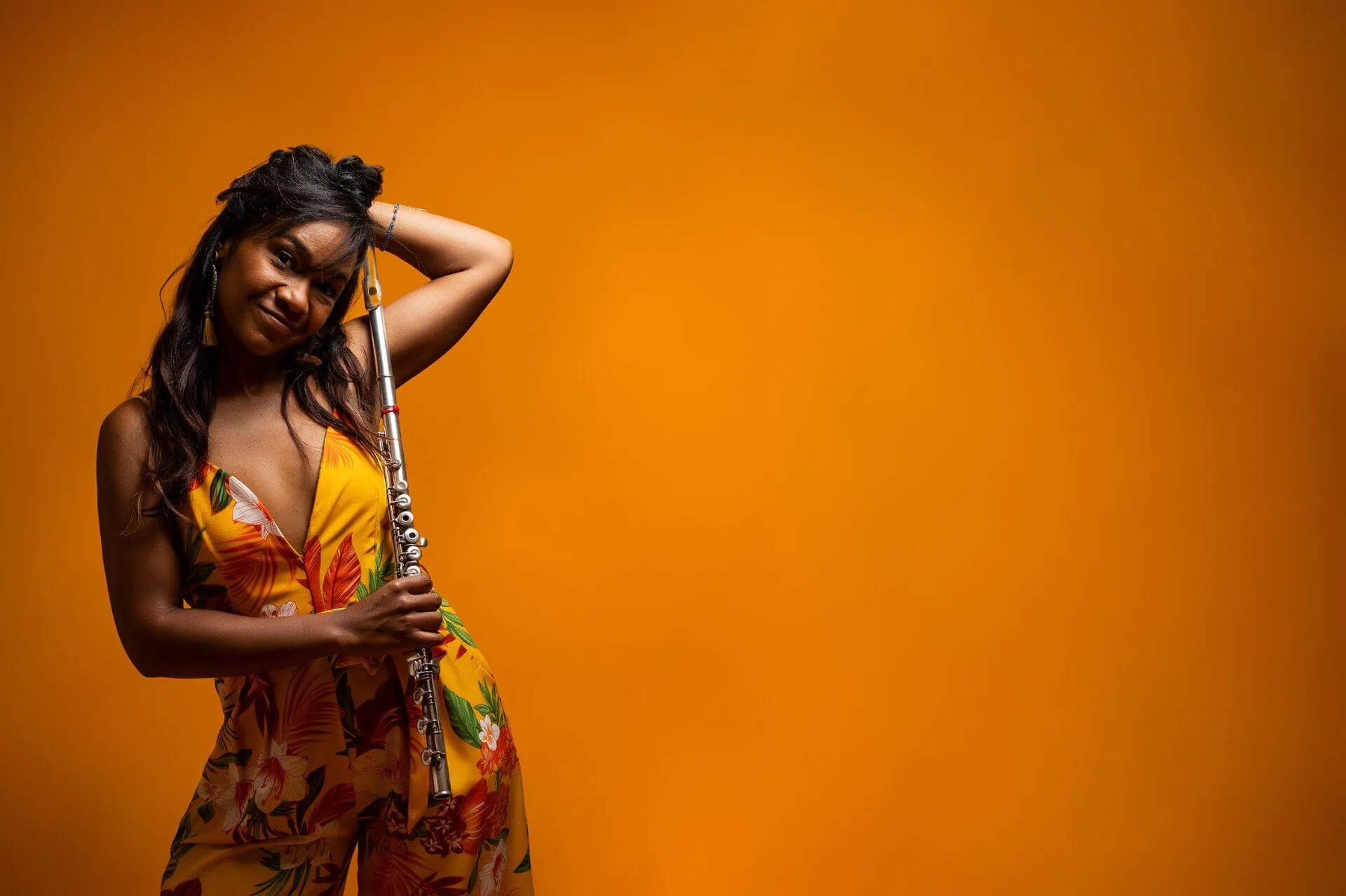 Magela Herrera holding her flute against an orange backdrop