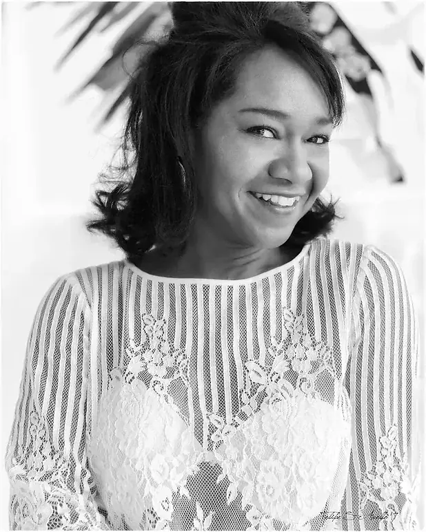 Black and white portrait of Magela Herrera smiling in a striped lace top